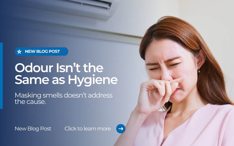 Woman covering her nose while standing indoors near an air conditioner, representing household odours and hygiene concerns.